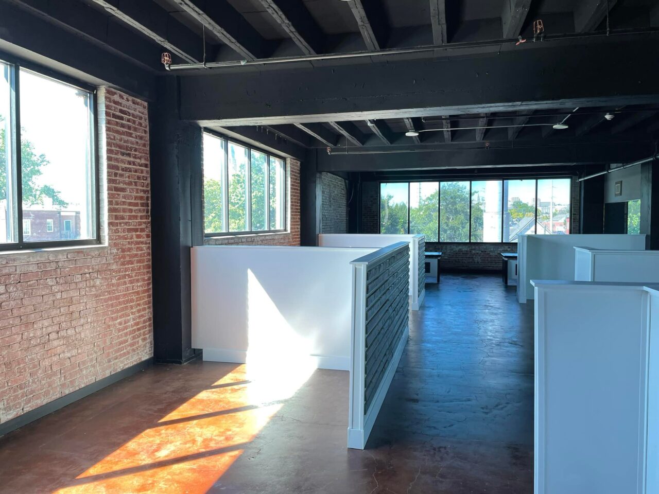 Open loft office with brick walls, black beams, and cubicles in The 1925 Building